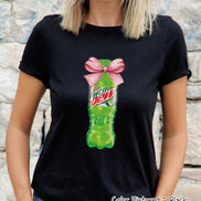 Black t-shirt featuring a graphic of a green Mountain Dew bottle tied with a pink bow. The Mountain Dew logo is visible on the bottle. The text 