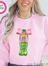 Pink sweatshirt featuring a graphic of a green soda bottle with a pink bow. The bottle has a green cap and the words "Mtn Dew" on it. The text "Color Pictured ~ Pink" is at the bottom. The sweatshirt has the Bella + Canvas logo.