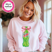 Pink sweatshirt featuring a graphic of a green Mountain Dew bottle tied with a pink bow. The sweatshirt has the text 
