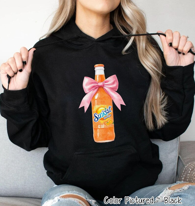 Black hooded sweatshirt featuring a graphic of a Sunkist Orange soda bottle with a pink bow. The bottle is orange with the Sunkist logo and the text 