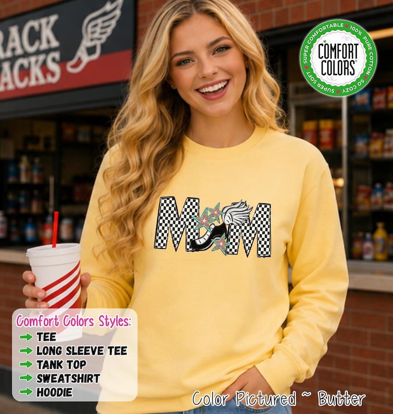 May include: A butter yellow long-sleeve sweatshirt featuring a graphic of the word MOM in a black and white checkered pattern. The letter O is replaced by a black and white winged shoe graphic surrounded by small teal and pink star illustrations.