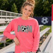 May include: A watermelon-colored long-sleeve sweatshirt featuring the word MOM in a black and white checkered pattern. The letter O is replaced by a black and white soccer ball graphic, accented with two colorful, multi-pointed star shapes.