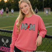 May include: A watermelon-colored crewneck sweatshirt featuring the word MOM in a black and white checkered pattern. The letter O is replaced by a red lacrosse ball with two crossed lacrosse sticks behind it, accented by two small blue star shapes.