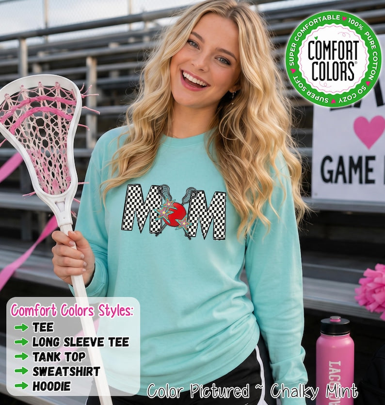 May include: A long-sleeve crewneck sweatshirt in chalky mint green featuring a graphic on the chest with the text MOM in a black and white checkered pattern, accented by two crossed lacrosse sticks and a red circle with small star details.