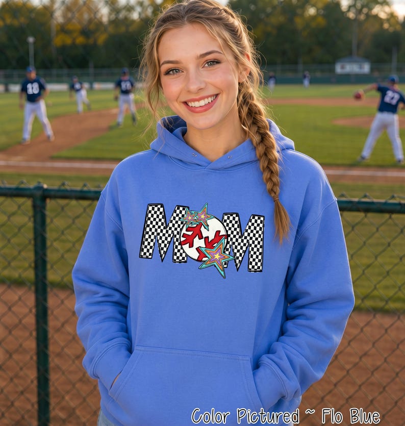 May include: A light blue hooded sweatshirt featuring a graphic on the chest with the word MOM in a black and white checkered pattern. The letter O is replaced by a white baseball with red stitching, accented by two colorful star shapes.