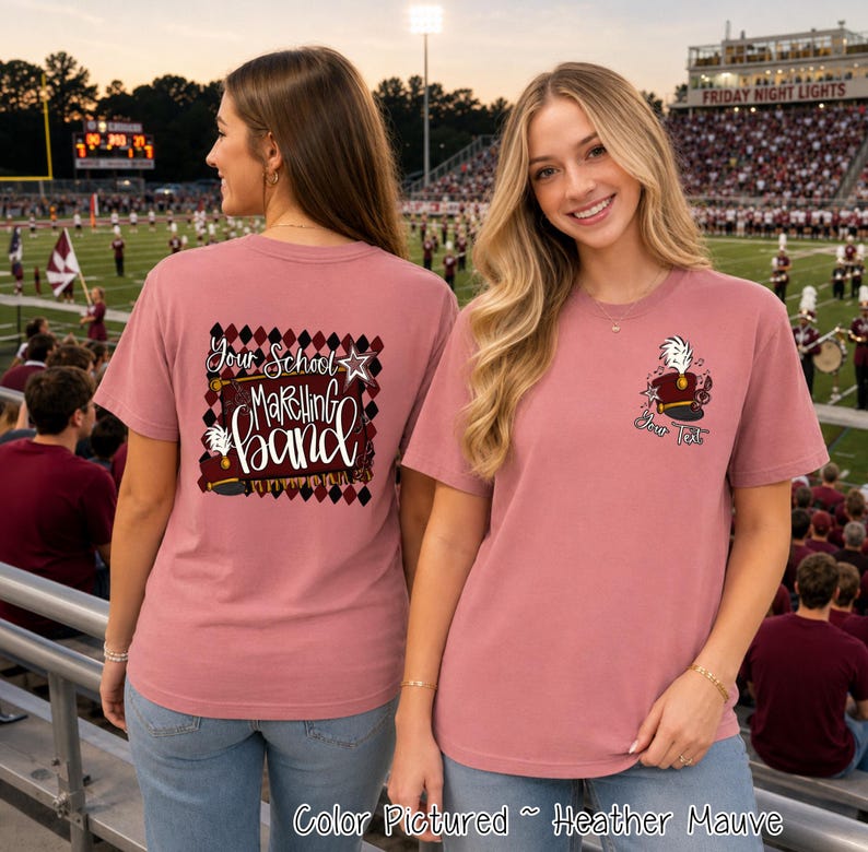 May include: A heather mauve t-shirt featuring a marching band theme. The back displays a diamond pattern with the text Your School Marching Band and a hat graphic. The front left chest shows a smaller marching band hat graphic with the text Your Text.