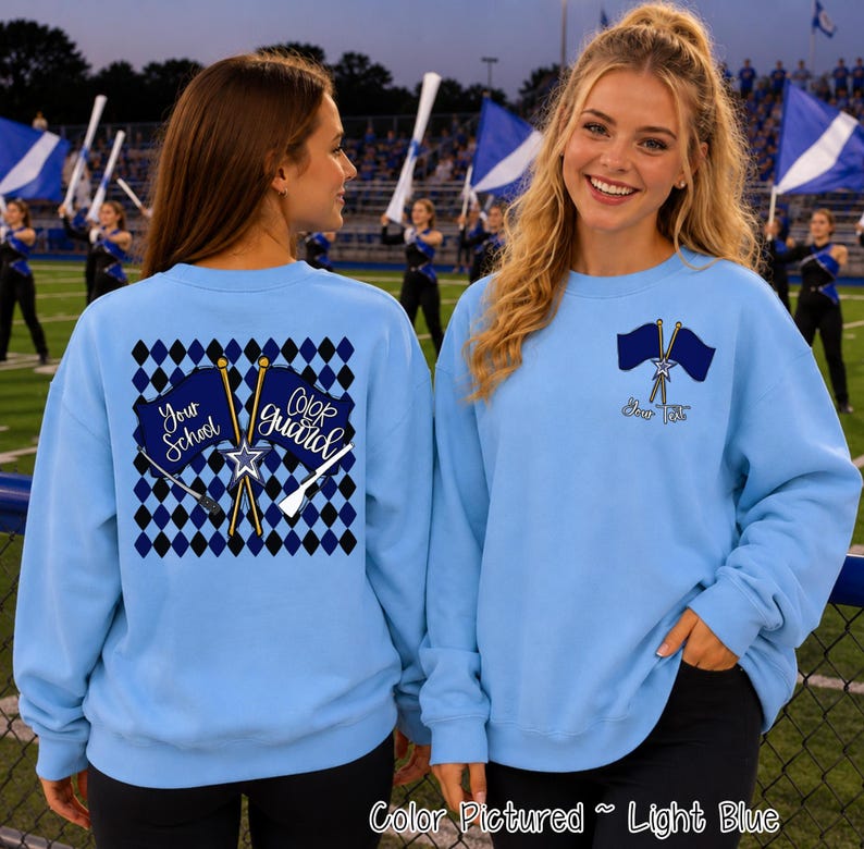 May include: A light blue crewneck sweatshirt featuring a back graphic of a black and blue diamond pattern with two crossed flags and the text Your School Color Guard. The front left chest displays two small crossed flags and the text Your Text.