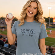 May include: A blue storm colored short-sleeve t-shirt featuring a black line art graphic of a baseball glove, a bow, and a baseball, with the text 