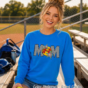 May include: A royal blue long-sleeve sweatshirt featuring the word MOM in a black and white checkered pattern. The letter O is replaced by a yellow softball graphic with red stitching, accented by two colorful, multi-pointed star shapes.