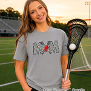 May include: A granite gray short-sleeve t-shirt featuring a graphic print of the word MOM in a black and white checkered pattern. The letter O is replaced by a red circle with two crossed lacrosse sticks and two teal stars layered on top.