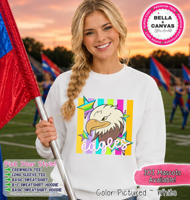 May include: A white crewneck sweatshirt featuring a graphic of a bald eagle head with a yellow beak and brown feathers. The design includes colorful vertical stripes in the background and multi-colored stars, with the word eagles in white script.