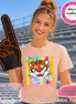 May include: A peach-colored crewneck t-shirt featuring a graphic of a tiger face surrounded by colorful stars and vertical stripes with the word tigers written below. The shirt is displayed with a black foam finger with orange trim and text.