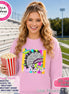 May include: A light pink crewneck sweatshirt featuring a graphic print of a feathered headdress in black, white, and purple, layered over colorful vertical stripes and stars, with the word indians written in white script lettering across the front.