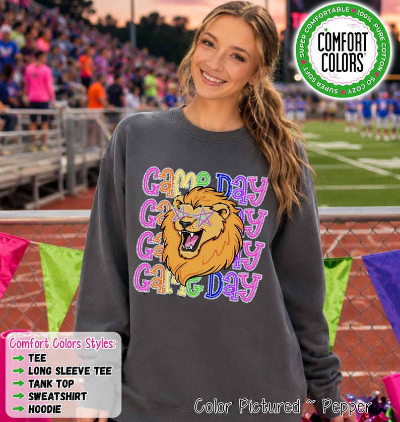 May include: A charcoal gray crewneck sweatshirt featuring a graphic of a roaring lion wearing star-shaped glasses. The text 