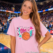 A light pink short-sleeve t-shirt featuring a graphic print with the text GAME DAY in pink letters, an orange basketball, a teal lightning bolt, a white megaphone, and various pink and teal stars surrounded by black polka dots.
