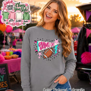 A granite gray long-sleeve shirt featuring a graphic print with the text GAME DAY in pink, a brown football, a teal and white pennant, a teal lightning bolt, and pink stars, surrounded by black dots on a gray fabric background.