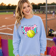 A light blue crewneck sweatshirt featuring a graphic print on the chest. The design includes a yellow softball, a white pennant with the text 